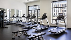 A gym with treadmills, a bench press, and large windows. - Kimpton Cottonwood by IHG (Omaha)