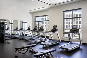 A gym with treadmills, a bench press, and large windows.