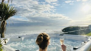 A person in a hot tub with a view of the ocean and a palm tree. - Luxury, Spacious, Beachfront (direct access) House with Breath-taking Sea Views (Downderry)