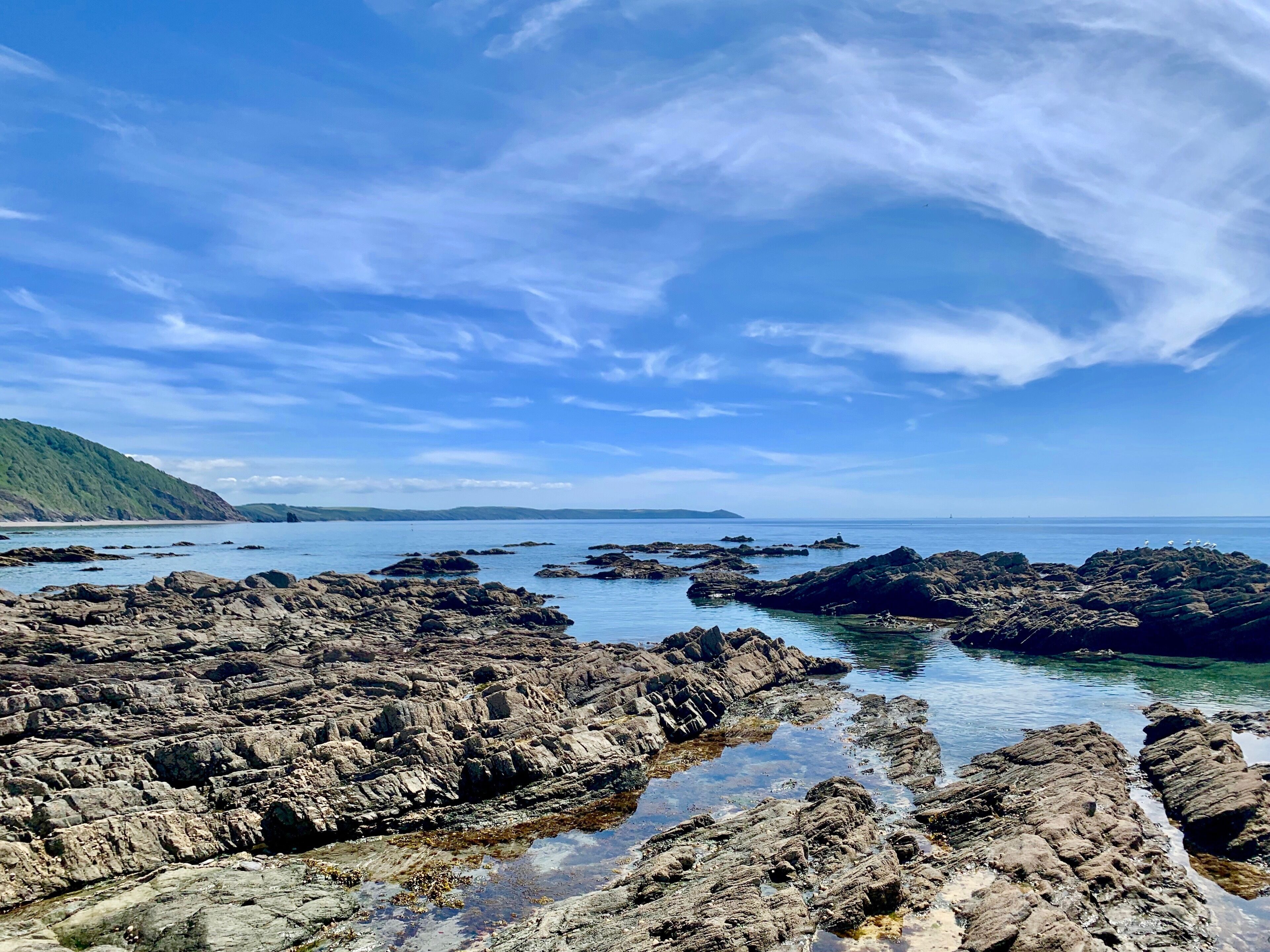Un paisaje costero rocoso con cielos azules despejados y aguas tranquilas.