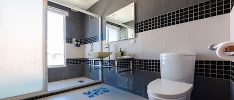 A modern bathroom with a glass shower enclosure, a white toilet, and a sink with a mirror above it.