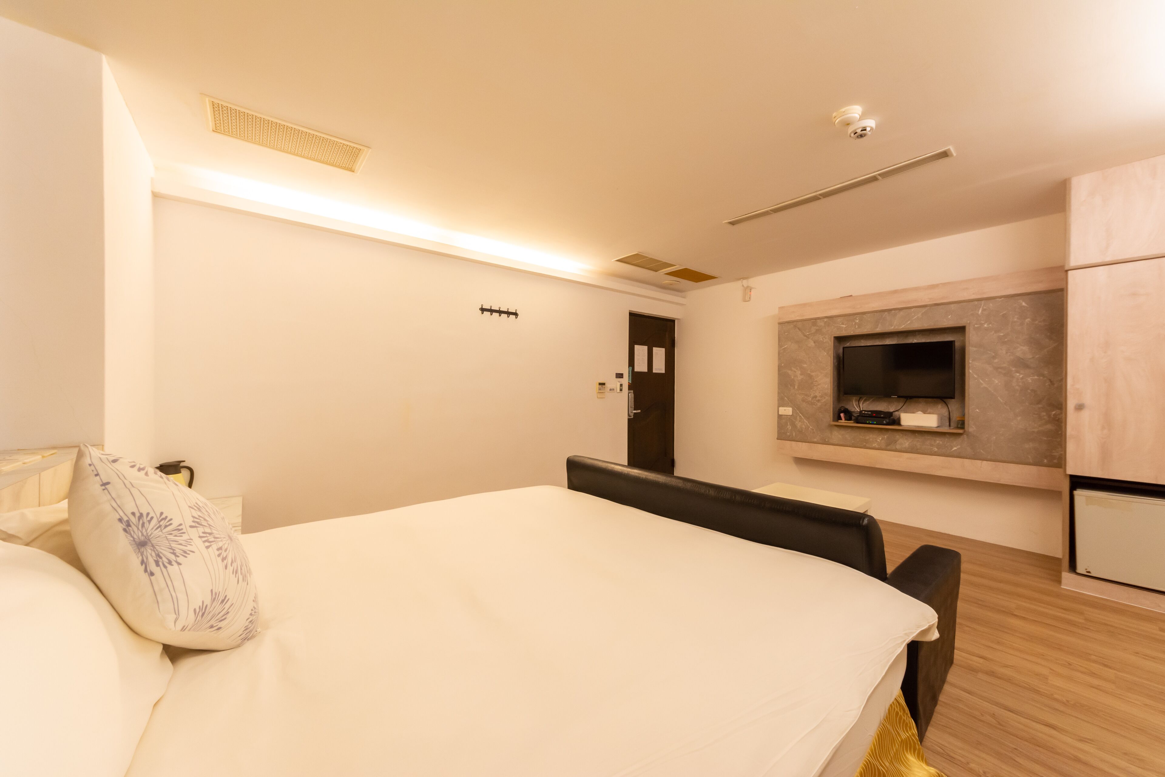 Quarto de hotel moderno com uma cama grande, uma escrivaninha e televisão integrada.