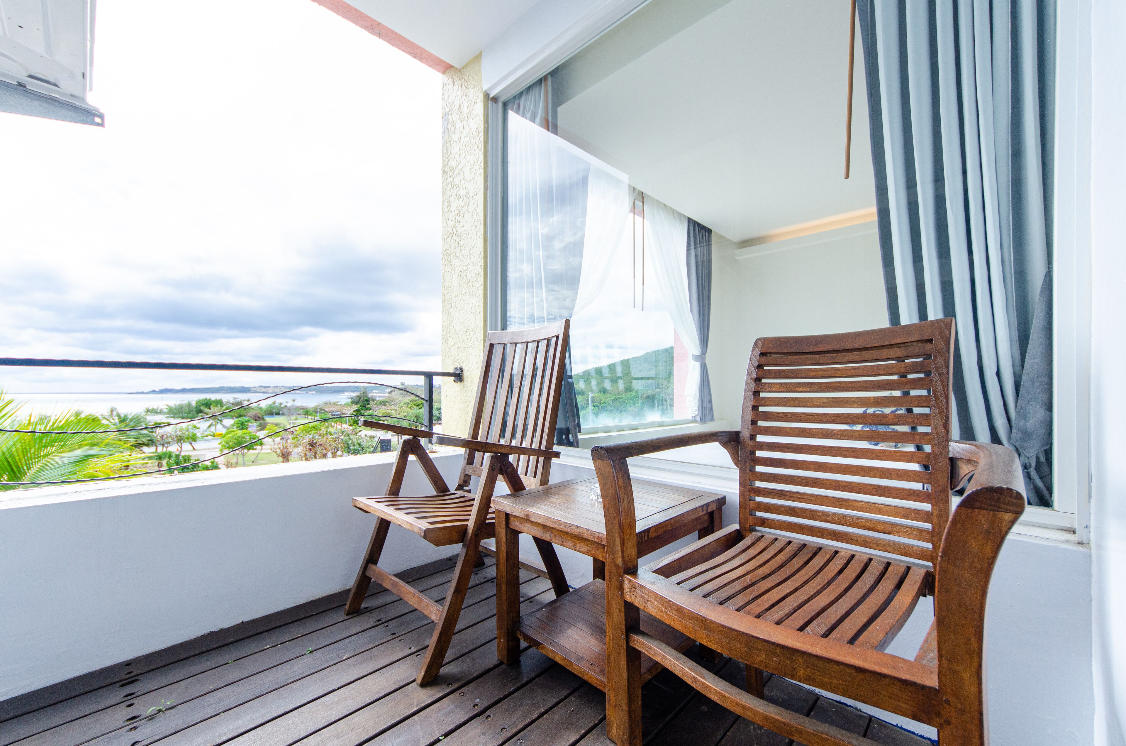 A balcony with wooden furniture and a view of the sea.
