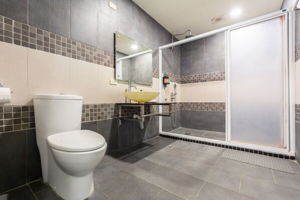 Un baño con inodoro, lavamanos, espejo y zona de ducha.
