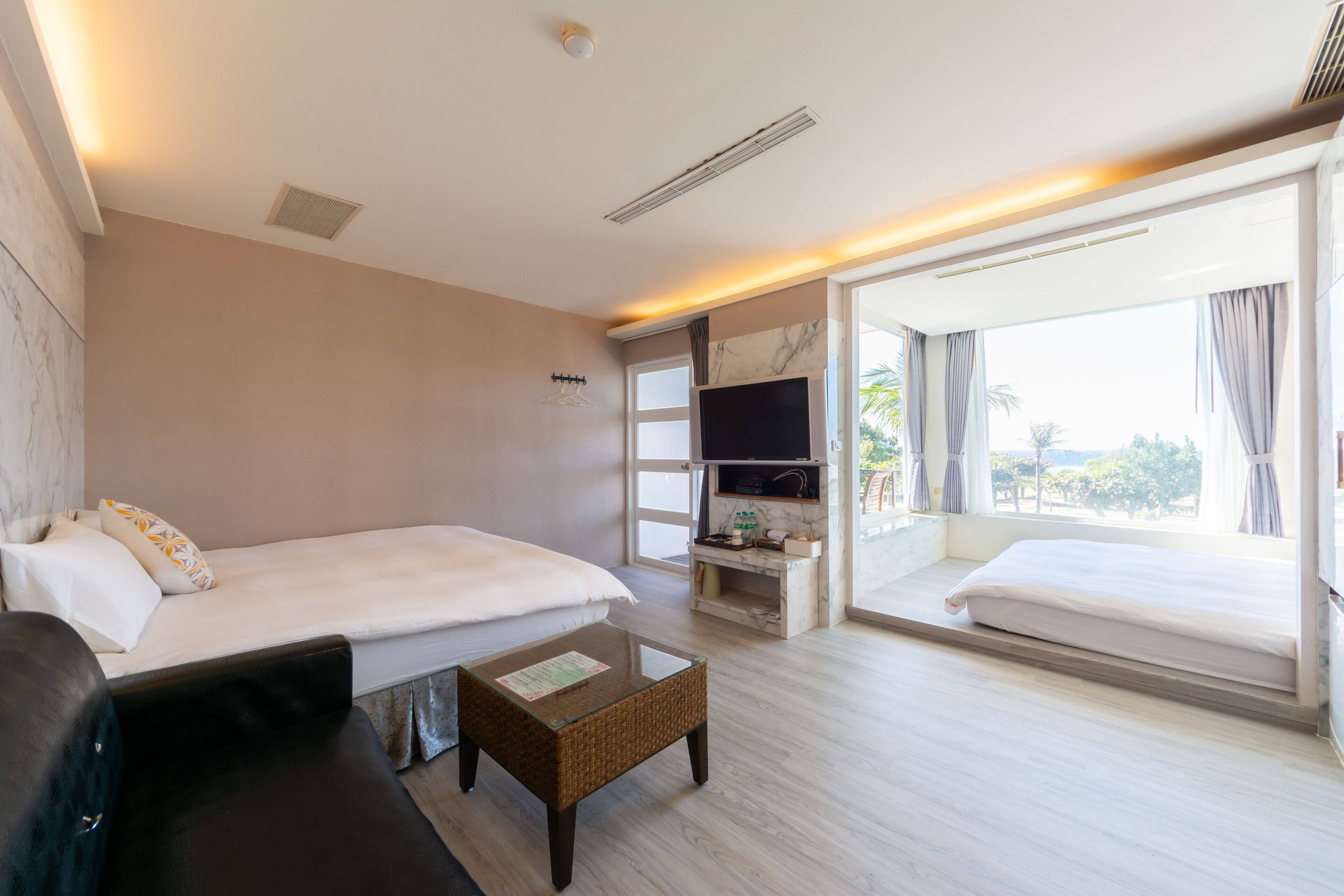 Una habitación de hotel con cama, televisión, una mesita y un ventanal grande.