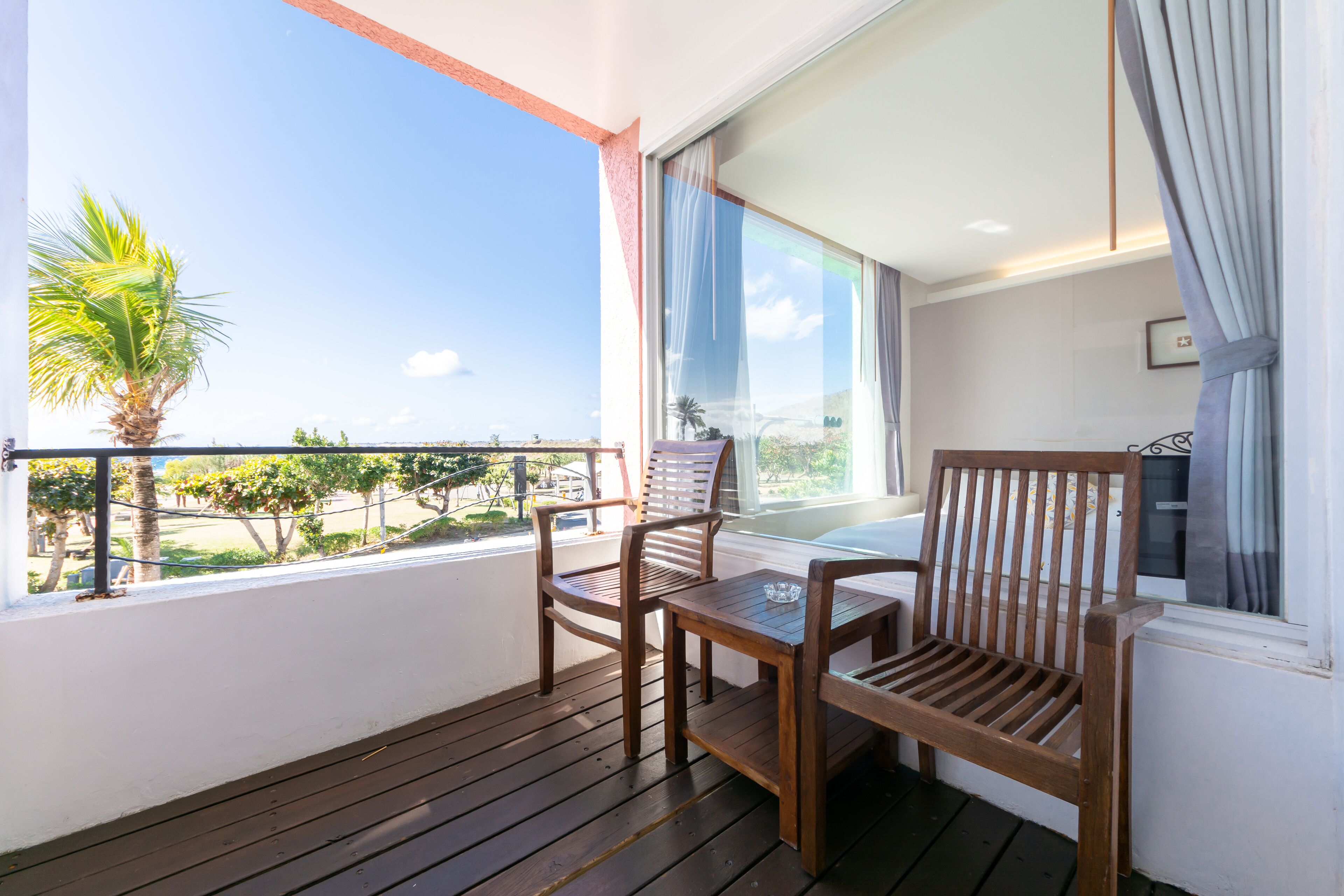 A balcony with wooden furniture and a view of the sea.