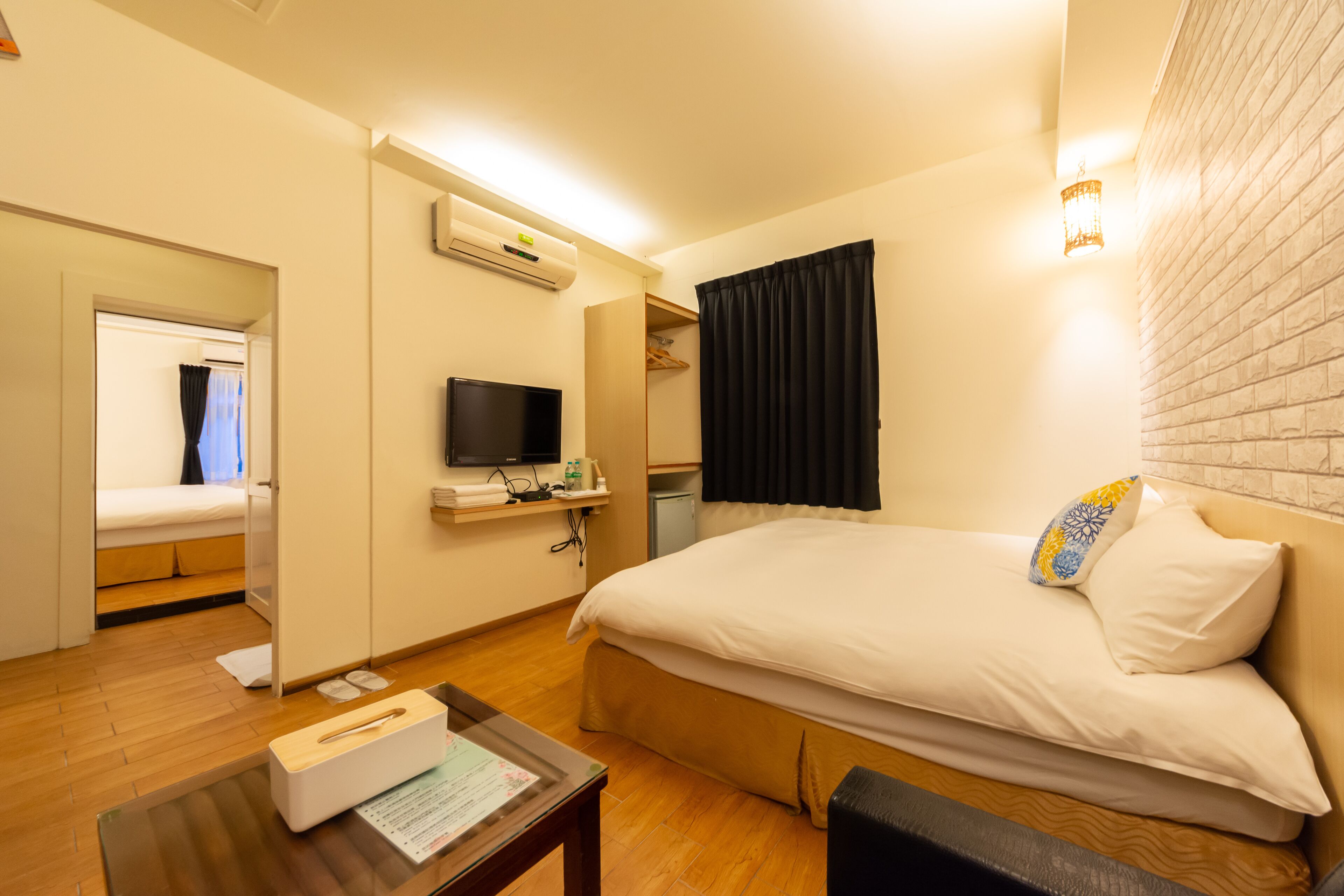 Quarto de hotel com uma cama, televisão, escrivaninha e espelho.
