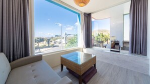 Uma sala de estar moderna com uma mesa de centro de vidro, um sofá e vista para o horizonte urbano através de grandes janelas.