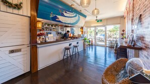 Interior de restaurante com balcão, banquetas e um mural de um barco na parede.