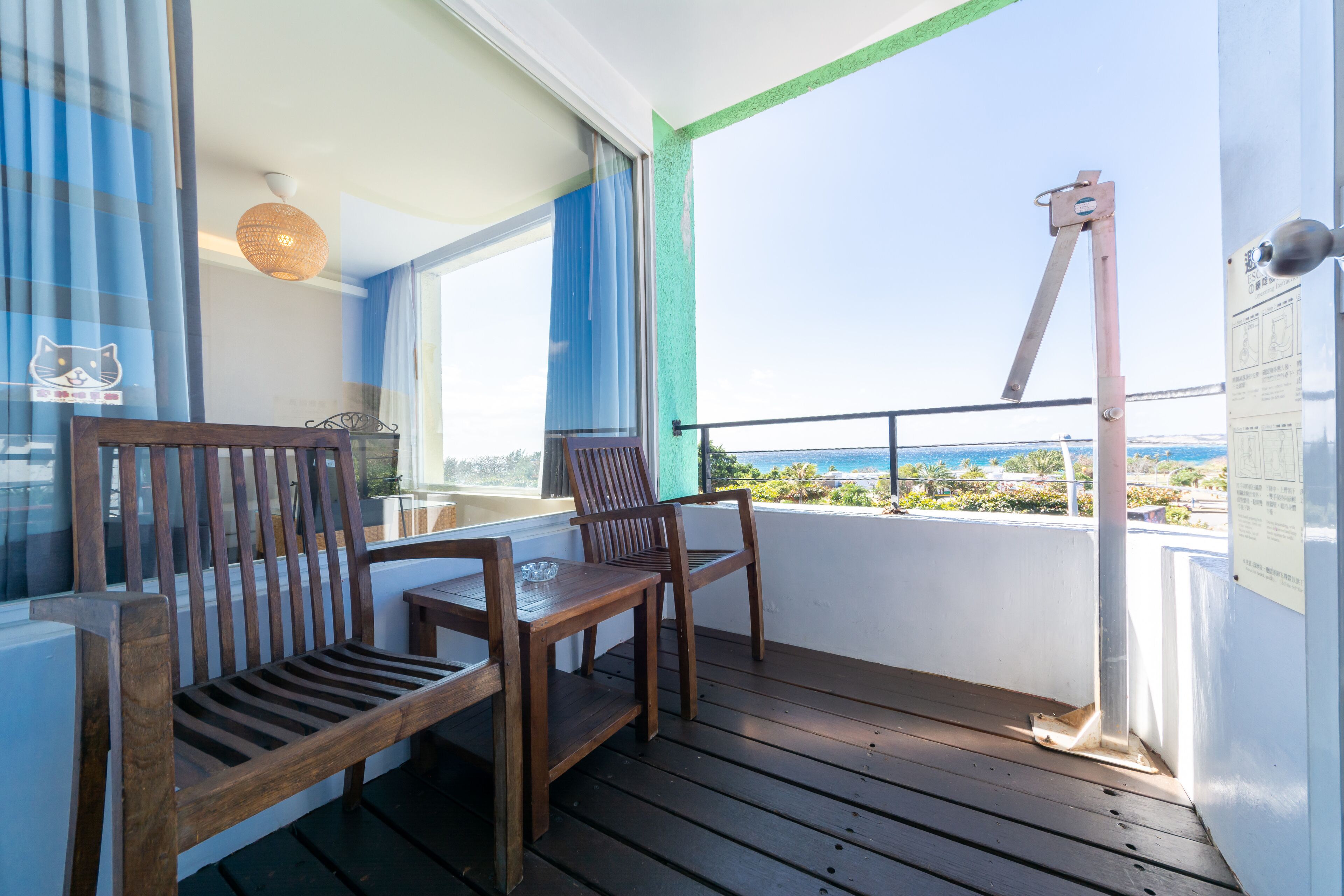 A balcony with wooden furniture, a view of the sea, and a metal structure.