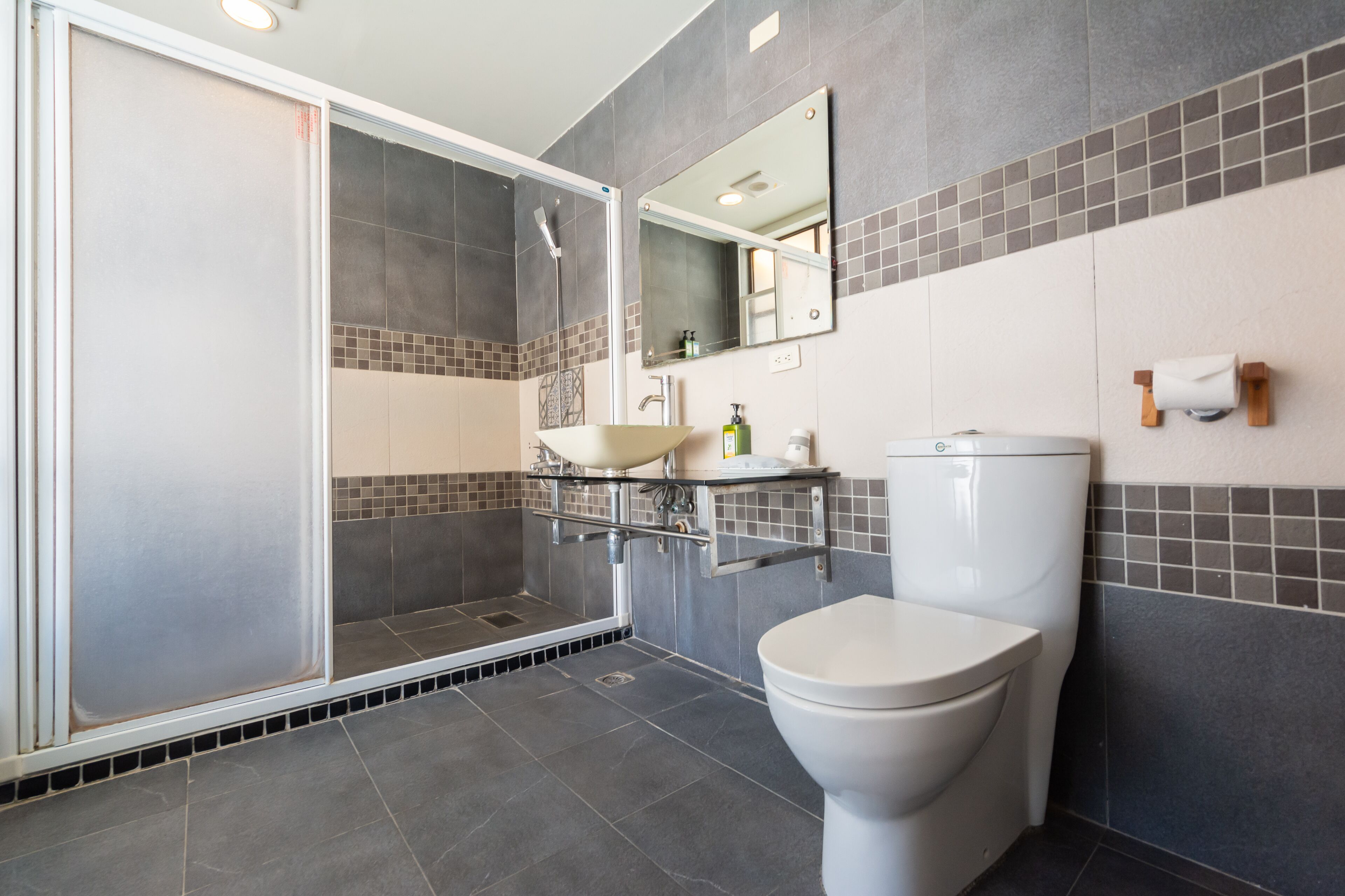 A modern bathroom with a glass-enclosed shower, a white toilet, and a glass sink.