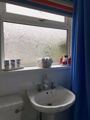 A bathroom with a window, a sink, and toiletries on the windowsill. - Remarkable 3-bed House in Durham (Durham)