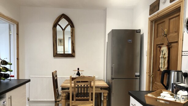 Eine Küche mit Holztisch, Stühlen, Kühlschrank, Wasserkocher und Kaffeemaschine.