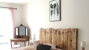 A bedroom with a large bed, a wooden headboard, a bedside table with a lamp, a mirror, and a framed artwork on the wall. - Apartment historic center Neufchâteau (Neufchâteau)