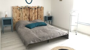 A bedroom with a wooden headboard, two bedside tables, a bed with grey bedding, and a small wall-mounted picture. - Apartment historic center Neufchâteau (Neufchâteau)