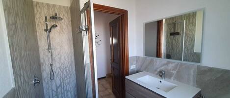 A bathroom with a walk-in shower, a sink, and a mirror.