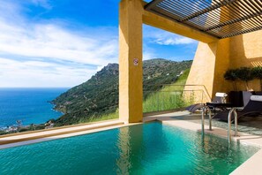 Una piscina infinita con vistas al mar y las montañas.