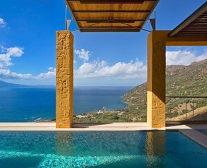Una piscina con vista despejada al mar y un paisaje montañoso.