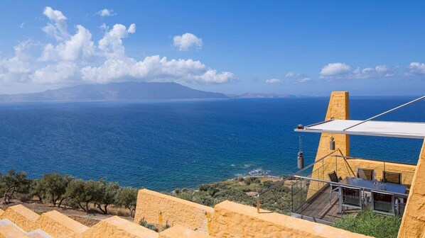 Una propiedad costera con terraza frente al mar, muro de piedra y una vista despejada del horizonte.