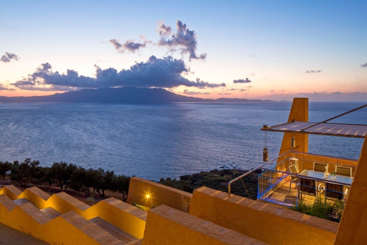 Une propriété située en bord de mer, dotée d’une terrasse avec vue sur la mer, d’un espace repas avec des sièges extérieurs et d’un escalier menant à la terrasse.