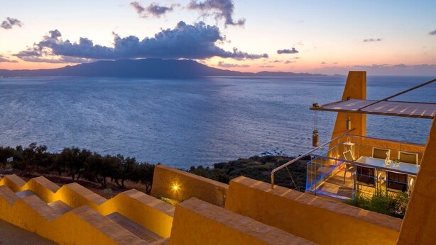 Una proprietà costiera con una terrazza vista mare, zona pranzo con posti a sedere all'aperto e una scala che conduce alla terrazza.