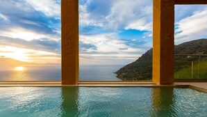 Una piscina a sfioro con vista sul mare e sul tramonto.