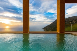 Una piscina infinita con vistas al mar y al atardecer.