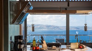 Una cucina con vista sul mare, dotata di una moka, una bottiglia d'olio d'oliva e diversi prodotti alimentari.