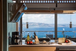 Cocina con vistas al mar, equipada con cafetera, una botella de aceite de oliva y diversos alimentos.