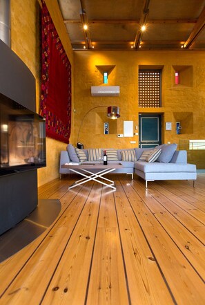 Una sala moderna con un sofá seccional, una chimenea y suelo de madera.