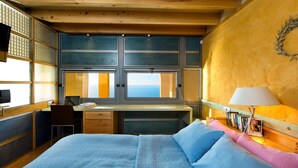 Una camera da letto con un letto, una scrivania, una sedia, una finestra e una lampada fissata al muro.