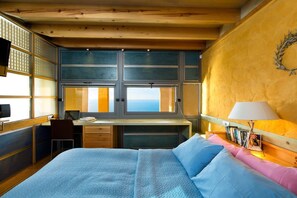 Un dormitorio con cama, escritorio, silla, ventana y lámpara de pared.