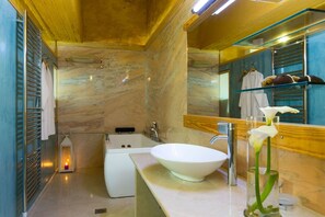 Un baño moderno con un lavamanos blanco, una bañera y un espejo grande.