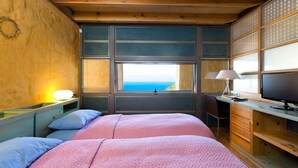 Ein Schlafzimmer mit einem großen Bett, einem Schreibtisch, einem Stuhl und einem Fenster mit Blick.