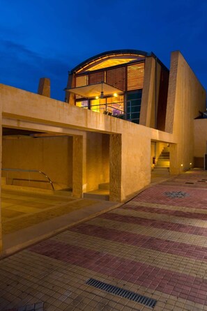 A modern building with a curved facade and a covered walkway leading to a staircase. - Eleni's Serenity - Discovering Sapphire Harmonies (Ravdoucha)