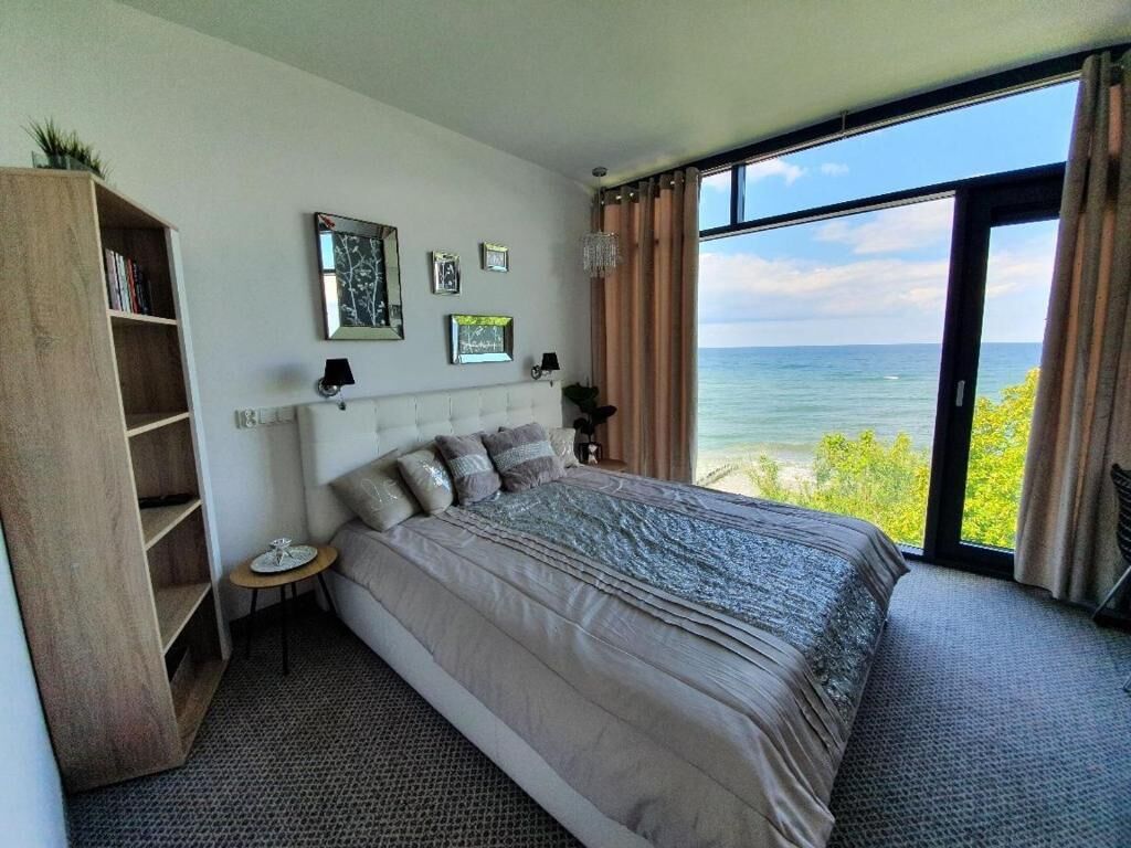 Une chambre avec un grand lit, une table de chevet, une bibliothèque et une vue sur l’océan.