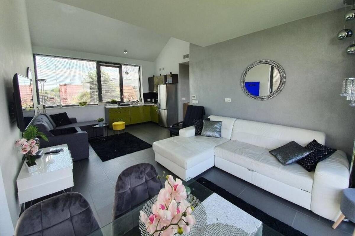 Una sala de estar moderna con un sofá blanco, una mesa de centro de vidrio y una zona de comedor con una silla amarilla.