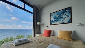 A bedroom with a large bed, a painting, and a view of the sea. - Apartamenty Boulevard - 365PAM (Ustronie Morskie)