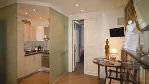 Een moderne keuken met houten kasten, een eethoek met een tafel en stoelen, en een gang naar een andere kamer.