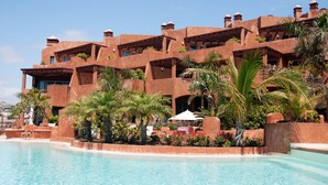 Un resort con piscina, mobiliario exterior y un edificio con varios balcones.