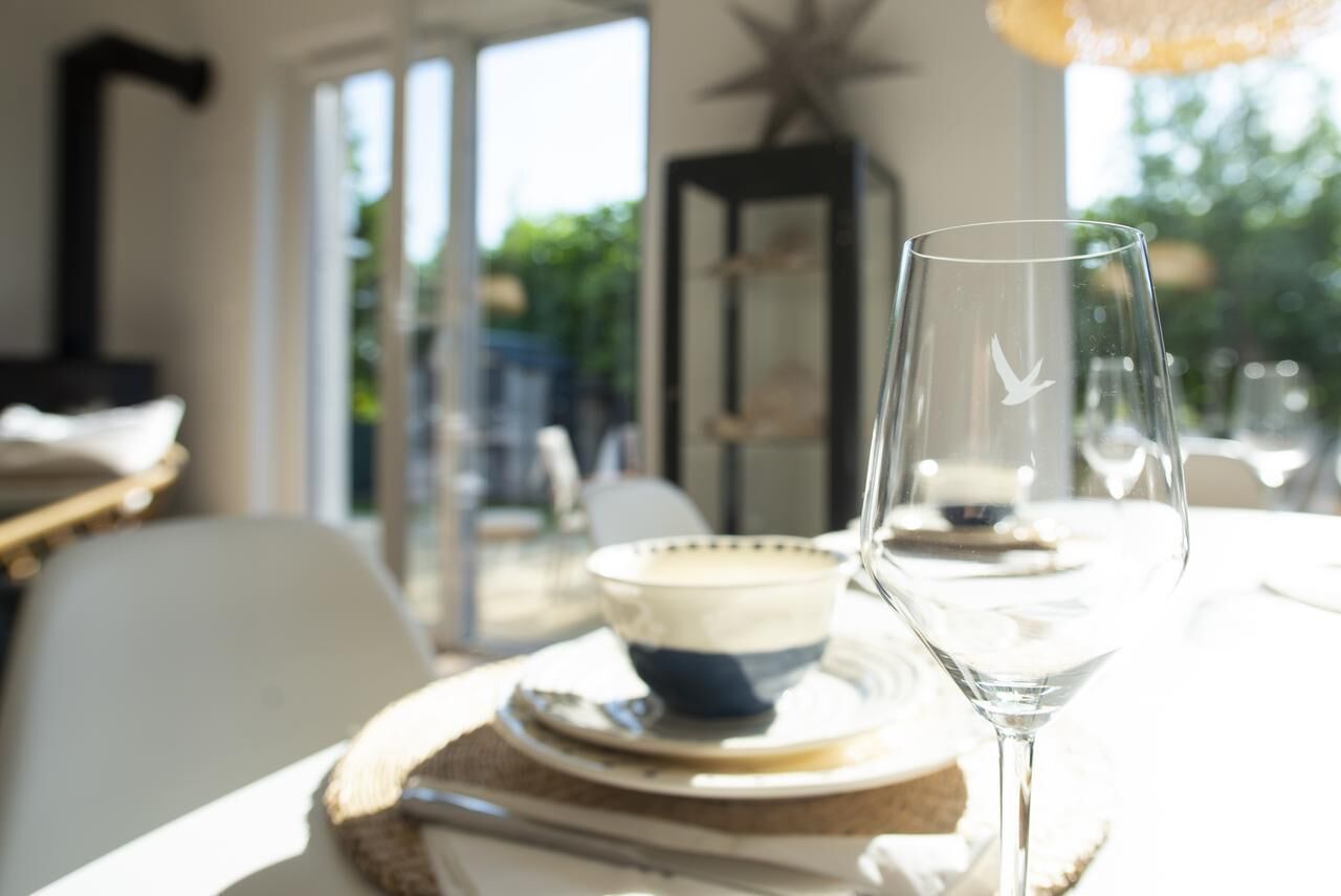 Uma mesa de jantar com um copo e uma tigela, uma cadeira e uma decoração em forma de estrela ao fundo.