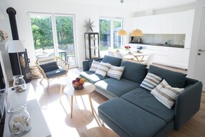 A modern living room with a sofa, a coffee table with fruit, a star decoration, and a view of the outdoors. - Apartament Marina - 365 PAM (Ustronie Morskie)