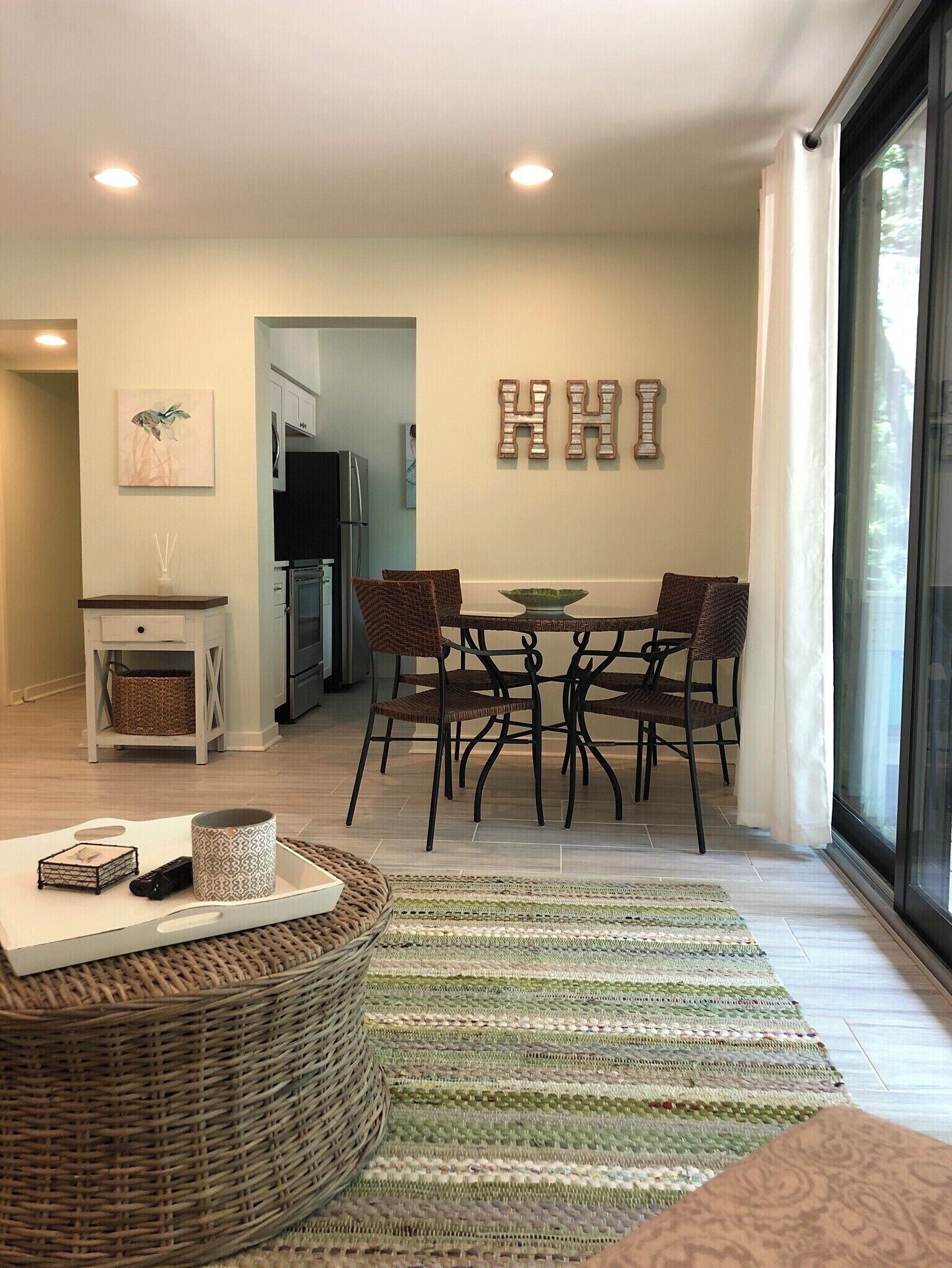 Un espace repas moderne avec une table ronde, quatre chaises et un élément décoratif mural qui forme les lettres « HHI ».