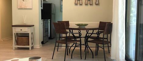 Uma área de refeições moderna com uma mesa redonda, quatro cadeiras e um painel decorativo com a inscrição 'HHI'.