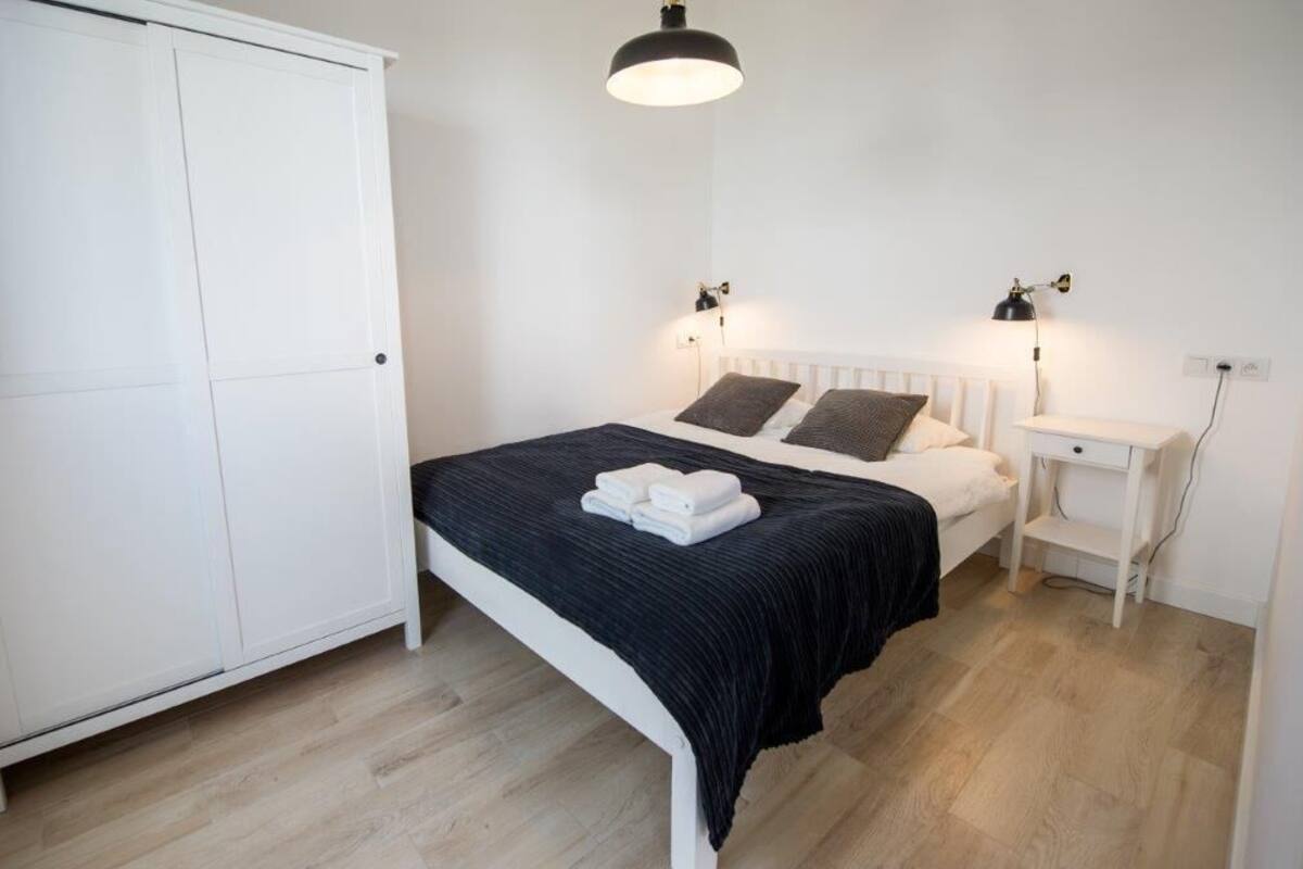 Ein Schlafzimmer mit Bett, Nachttischen, einem Kleiderschrank und einer Hängeleuchte.