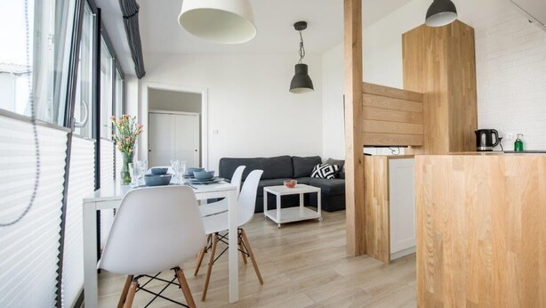 A modern living space with a dining area, a sofa, and a kitchen counter. - Apartamenty Stella Mare - 365 PAM (Ustronie Morskie)