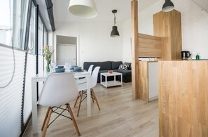 A modern living space with a dining area, a sofa, and a kitchen counter. - Apartamenty Stella Mare - 365 PAM (Ustronie Morskie)