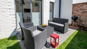 A modern outdoor patio with wicker furniture, a red lantern, and a barbecue grill. - Apartamenty Stella Mare - 365 PAM (Ustronie Morskie)