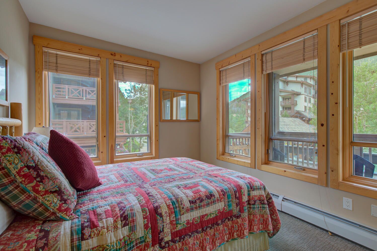 Une chambre à coucher avec un grand lit, de nombreuses fenêtres et une vue sur un bâtiment à l’extérieur.