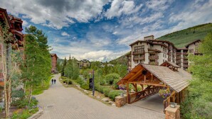 Eine Lodge mit überdachter Veranda, gepflasterten Wegen und umliegender Bepflanzung.
